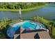 Scenic aerial view of a community pool with lounge chairs and a picturesque lake with fountain at 12730 Oak Hill Way, Parrish, FL 34219