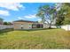 Spacious backyard with green grass, a white fence, mature trees, and an enclosed patio at 13911 Briardale Ln, Tampa, FL 33618