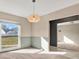 Bright dining area featuring carpet flooring, wainscoting, a modern light fixture, and a view of the yard at 13911 Briardale Ln, Tampa, FL 33618