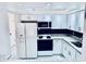 Bright kitchen with white cabinets, granite countertops, and black backsplash at 1620 58Th Ave. S. # 1, St Petersburg, FL 33712