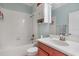 Cozy bathroom with a shower-tub combo, white tile surround, and cherry vanity at 20427 Carolina Cherry Ct, Tampa, FL 33647