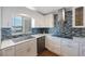 The kitchen has modern appliances, white cabinetry, and a stylish tiled backsplash by the window at 215 Valencia Blvd # 205, Belleair Bluffs, FL 33770