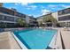 Large community pool surrounded by lounge chairs and lush tropical landscaping at 215 Valencia Blvd # 205, Belleair Bluffs, FL 33770