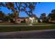 Exterior view of home featuring a lush green lawn, mature trees and a modern entrance at twilight at 217 Manatee Rd, Belleair, FL 33756