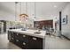 Modern kitchen boasts a large island with a sink, dark cabinetry, and sleek pendant lighting at 217 Manatee Rd, Belleair, FL 33756