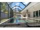 Outdoor pool with spa features a screened enclosure and patio area with stone tiling at 217 Manatee Rd, Belleair, FL 33756