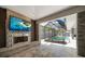 The screened pool area showcases a stone fireplace with TV, seamlessly blending indoor and outdoor living spaces for relaxation at 217 Manatee Rd, Belleair, FL 33756