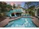 Spacious backyard oasis with a pool, tiki bar, lounge chairs, and a two-story house with a deck at 235 Aberdeen St, Dunedin, FL 34698