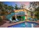 Inviting backyard with pool, patio, tiki bar, string lights, and lush greenery, perfect for outdoor entertaining at 235 Aberdeen St, Dunedin, FL 34698