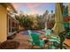 A backyard oasis complete with a pool, fire pit, patio furniture, lush greenery, tiki bar, and string lights at 235 Aberdeen St, Dunedin, FL 34698