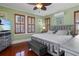 Bedroom with wood floors, gray bed frame, gray ottoman, and wood shuttered windows at 235 Aberdeen St, Dunedin, FL 34698