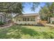 Charming single-story home featuring a well-manicured lawn, lush landscaping, and inviting covered front porch at 235 Aberdeen St, Dunedin, FL 34698