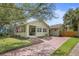 Charming home with a well-manicured lawn, brick driveway, detached garage, and inviting covered front porch at 235 Aberdeen St, Dunedin, FL 34698