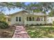 Charming home featuring a brick walkway, well-manicured lawn, and inviting covered front porch with a flag at 235 Aberdeen St, Dunedin, FL 34698