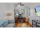 Cozy living room with hardwood floors, ceiling fan, and a dedicated workspace featuring dual monitors and a comfortable chair at 235 Aberdeen St, Dunedin, FL 34698