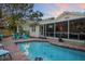 Backyard oasis with a sparkling pool, patio seating, and an adjacent screened-in porch for outdoor enjoyment at 235 Aberdeen St, Dunedin, FL 34698