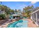 A tropical backyard retreat showcasing a sparkling pool, tiki bar, lounge area, and lush landscaping at 235 Aberdeen St, Dunedin, FL 34698