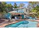 Outdoor pool and tiki bar with patio seating and lush landscaping create an inviting backyard oasis at 235 Aberdeen St, Dunedin, FL 34698