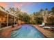 Relaxing pool with brick surround, tropical landscaping, and outdoor lighting for evening enjoyment at 235 Aberdeen St, Dunedin, FL 34698