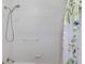A clean and bright white tiled shower with a detachable shower head and grab bar for added safety at 235 Aberdeen St, Dunedin, FL 34698