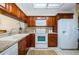 Well-lit kitchen with wooden cabinets, granite countertops, white appliances, and white tile flooring at 2749 Countryside Blvd # 28, Clearwater, FL 33761