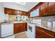 Charming kitchen with wood cabinets, white appliances, granite countertops, and white tile flooring at 2749 Countryside Blvd # 28, Clearwater, FL 33761
