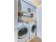 Efficient laundry closet with side-by-side washer and dryer units and ample shelving space at 2749 Countryside Blvd # 28, Clearwater, FL 33761
