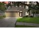 Two story home featuring a two car garage, neutral paint, dark shutters, landscaped yard and mature trees at 4821 Barchetta Dr, Land O Lakes, FL 34639