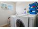 Practical laundry room with modern washer and dryer, storage shelves, and natural light from the window at 4821 Barchetta Dr, Land O Lakes, FL 34639
