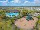 Aerial view of community pool, playground, and amenity area surrounded by palm trees and lush landscaping at 4904 Eagle Rock Dr, Wimauma, FL 33598