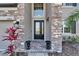Close-up of the front door with decorative stone accents, elegant lighting, and lush landscaping at 4904 Eagle Rock Dr, Wimauma, FL 33598