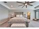 Spacious bedroom boasts a tray ceiling, ceiling fan and a seating bench at the foot of the bed at 4904 Eagle Rock Dr, Wimauma, FL 33598