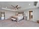 Large bedroom with a tray ceiling, ceiling fan, and an adjacent ensuite bathroom and second floor access at 4904 Eagle Rock Dr, Wimauma, FL 33598