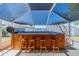 This screened in lanai features a hot tub with wooden surround that has a bar top and seating for four at 663 Allegheny Dr, Sun City Center, FL 33573