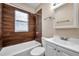 Bathroom with white vanity, white tub, and unique wood-look tile accent wall at 689 Paris S Ave, St Petersburg, FL 33701