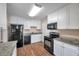 Kitchen with white cabinetry, black appliances, granite countertops, and wood-look flooring at 689 Paris S Ave, St Petersburg, FL 33701