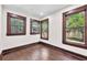 A cozy bedroom featuring three windows with dark wood trim and hardwood floors at 710 E Plymouth St, Tampa, FL 33603