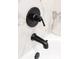 Close-up of a bathtub faucet with sleek, modern matte black fixtures and a marbled tile surround at 710 Seminole, Clearwater, FL 33755