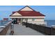 View of the pier building with a red metal roof and tan siding, extending over the ocean at 710 Seminole, Clearwater, FL 33755
