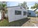 Side of a white building with black window frames surrounded by green lawn and palm trees at 7105 Blind Pass Rd, St Pete Beach, FL 33706