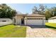 Charming single-story home featuring a brick-paved driveway, manicured lawn, and a two-car garage at 818 S Main St, Brooksville, FL 34601