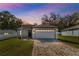 Charming single-story home at twilight featuring a brick-paved driveway, manicured lawn, and a two-car garage at 818 S Main St, Brooksville, FL 34601