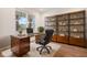 Staged office boasts a large desk, built-in shelving, and a window with views of the front yard at 8337 Abalone Loop, Parrish, FL 34219