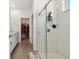 Modern bathroom with glass shower, white tile, and wood-look tile floors and an adjoining closet at 9802 Carabiner Way, Land O Lakes, FL 34637