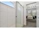 Bathroom showcasing the walk-in shower with glass doors, white subway tile and view of a bedroom at 9802 Carabiner Way, Land O Lakes, FL 34637