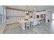 Kitchen with white cabinets, a large central island and adjacent breakfast bar with modern pendant lighting at 12851 Tortoise Shell Pl, Riverview, FL 33579