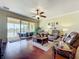 Bright living room with hardwood floors, comfortable furniture, and serene lake views through sliding glass doors at 16145 Amethyst Key Dr, Wimauma, FL 33598