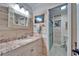 Charming bathroom with a granite vanity, framed mirror, and a beautifully tiled walk-in shower at 1710 New Bedford Dr, Sun City Center, FL 33573