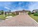 Charming single-story home featuring a brick driveway, lush landscaping, and an attached two-car garage at 1710 New Bedford Dr, Sun City Center, FL 33573