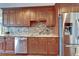 Kitchen featuring stainless steel appliances, custom wood cabinetry, granite countertops, and mosaic backsplash at 1710 New Bedford Dr, Sun City Center, FL 33573